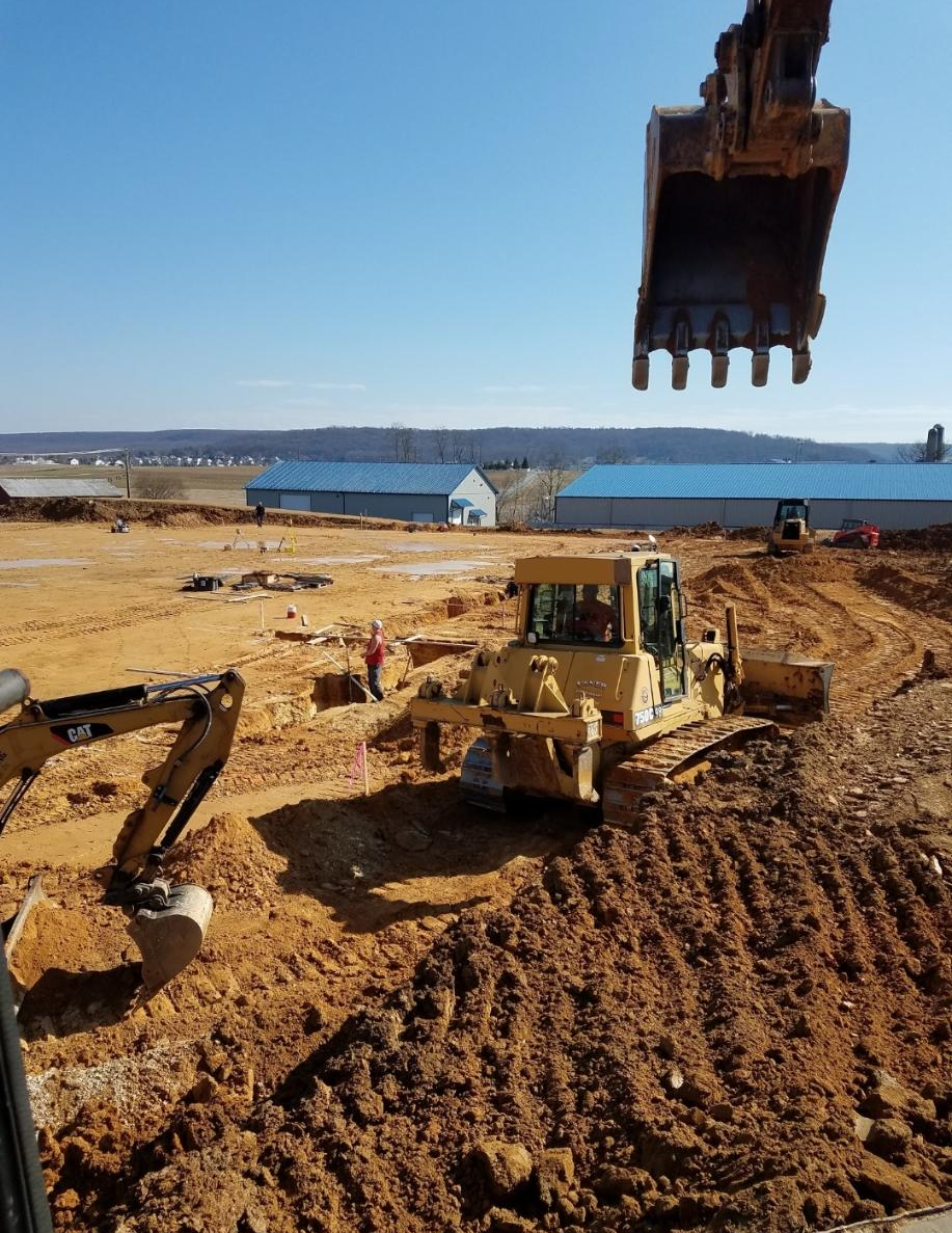A bulldozer is digging a hole in a dirt field.