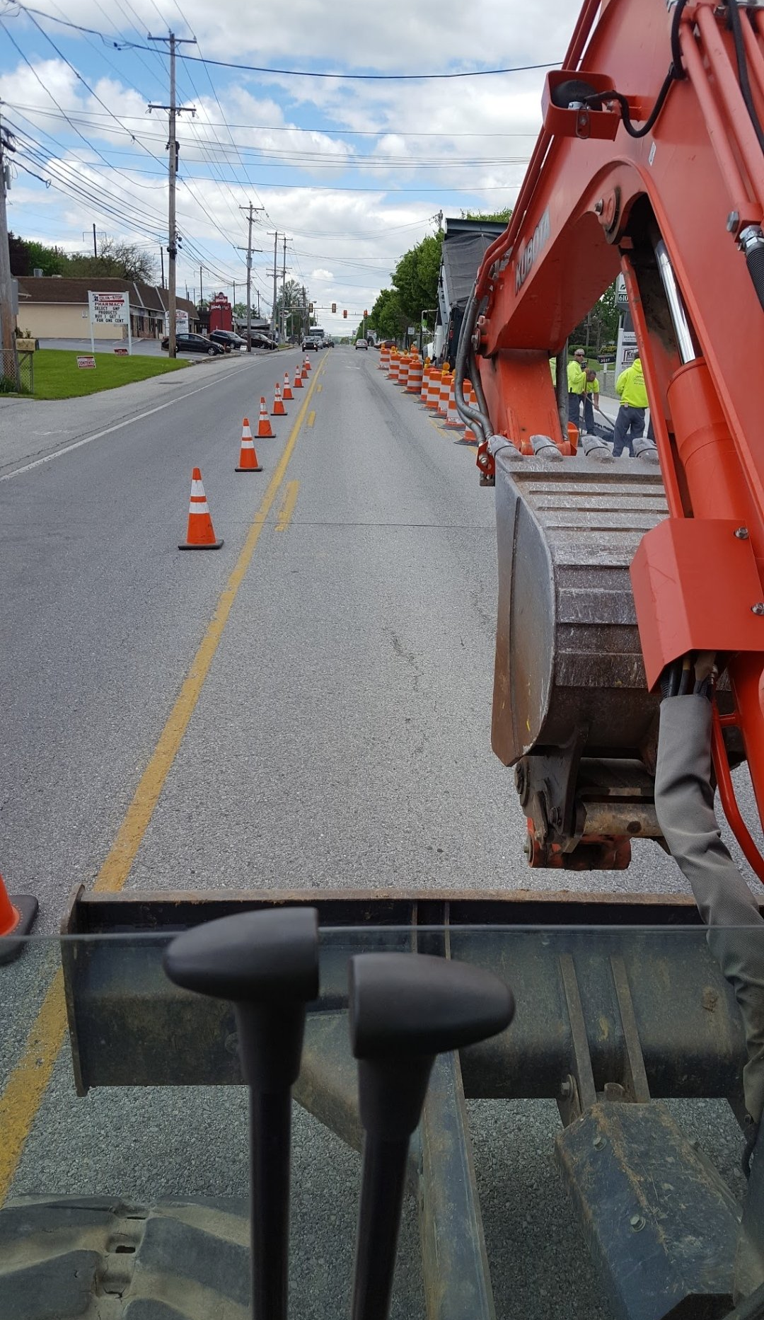 A large orange excavator is sitting on the side of a road.