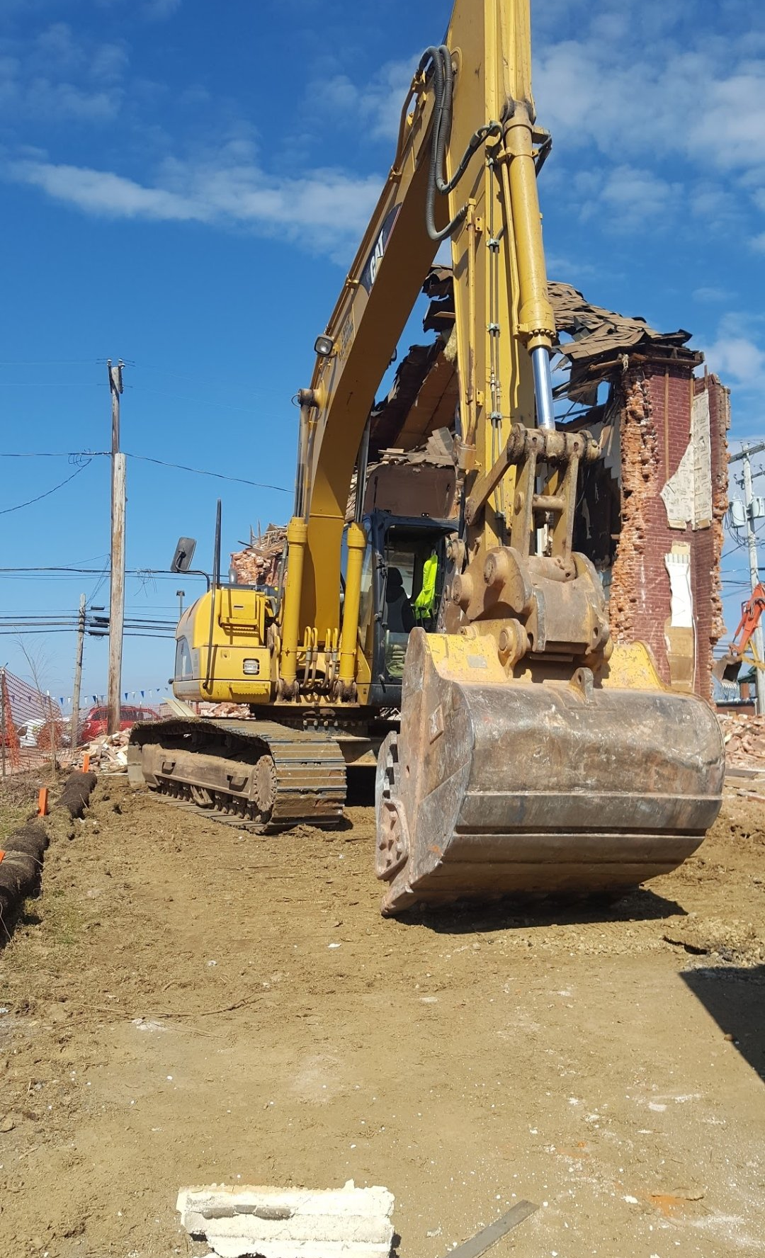 A large yellow excavator is demolishing a building.
