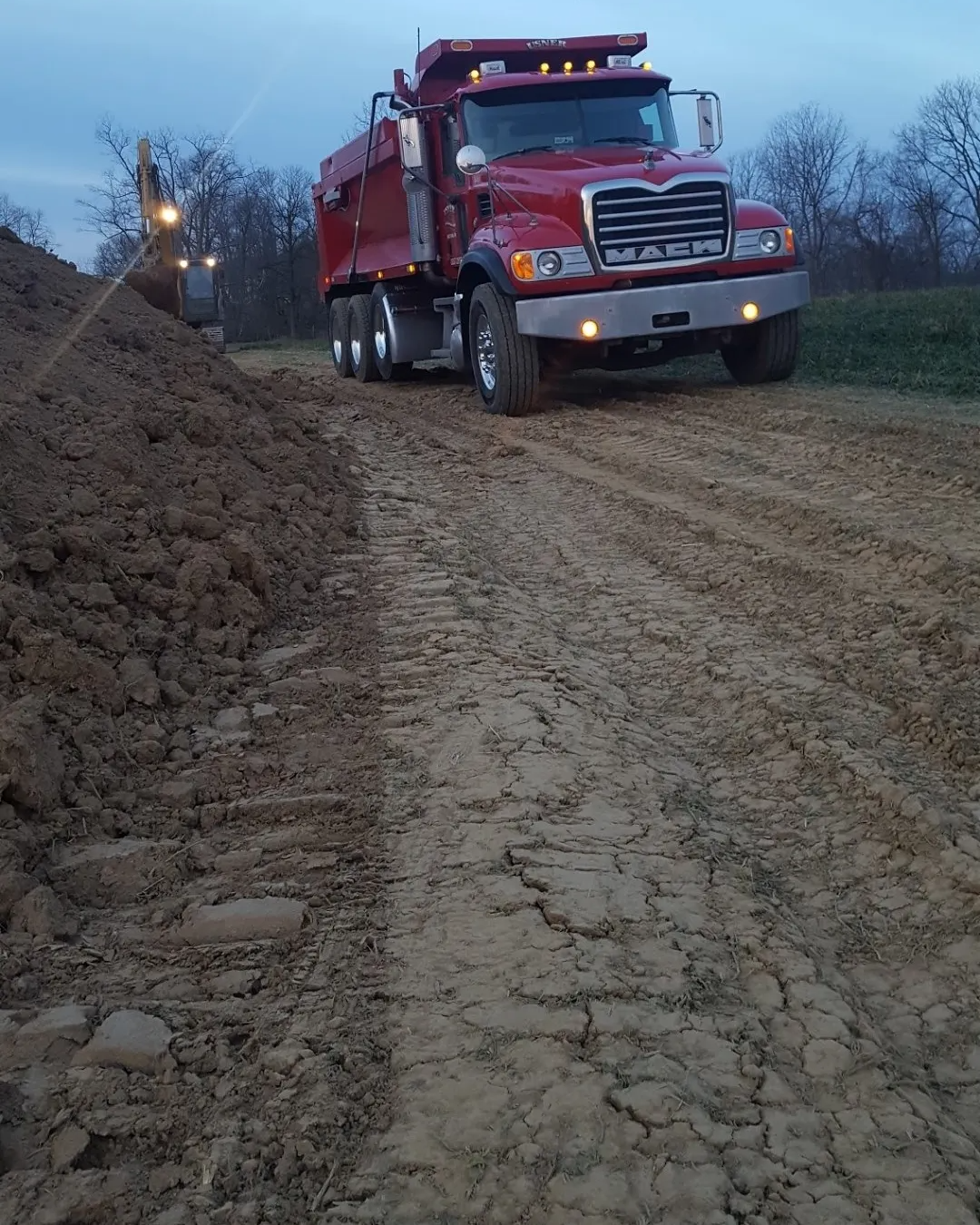 A red dump truck is driving down a dirt road
