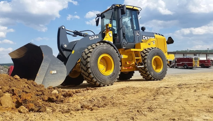 A yellow and black wheel loader is driving through a dirt field.