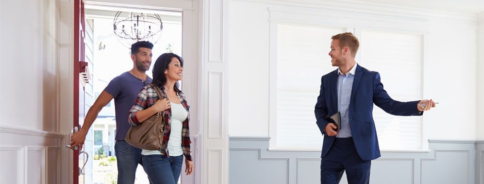 Real estate agent showing a home to a couple at the front door