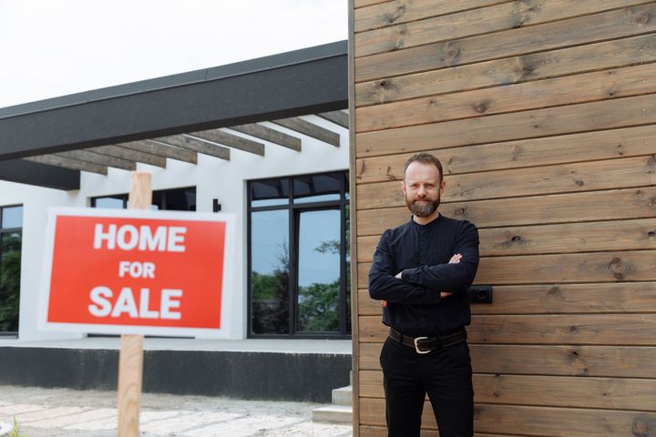 Real estate broker Mike Reppy smiles in front of a home.