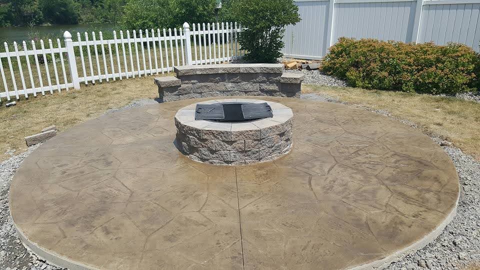 Circular patio with fire pit and seating in backyard.