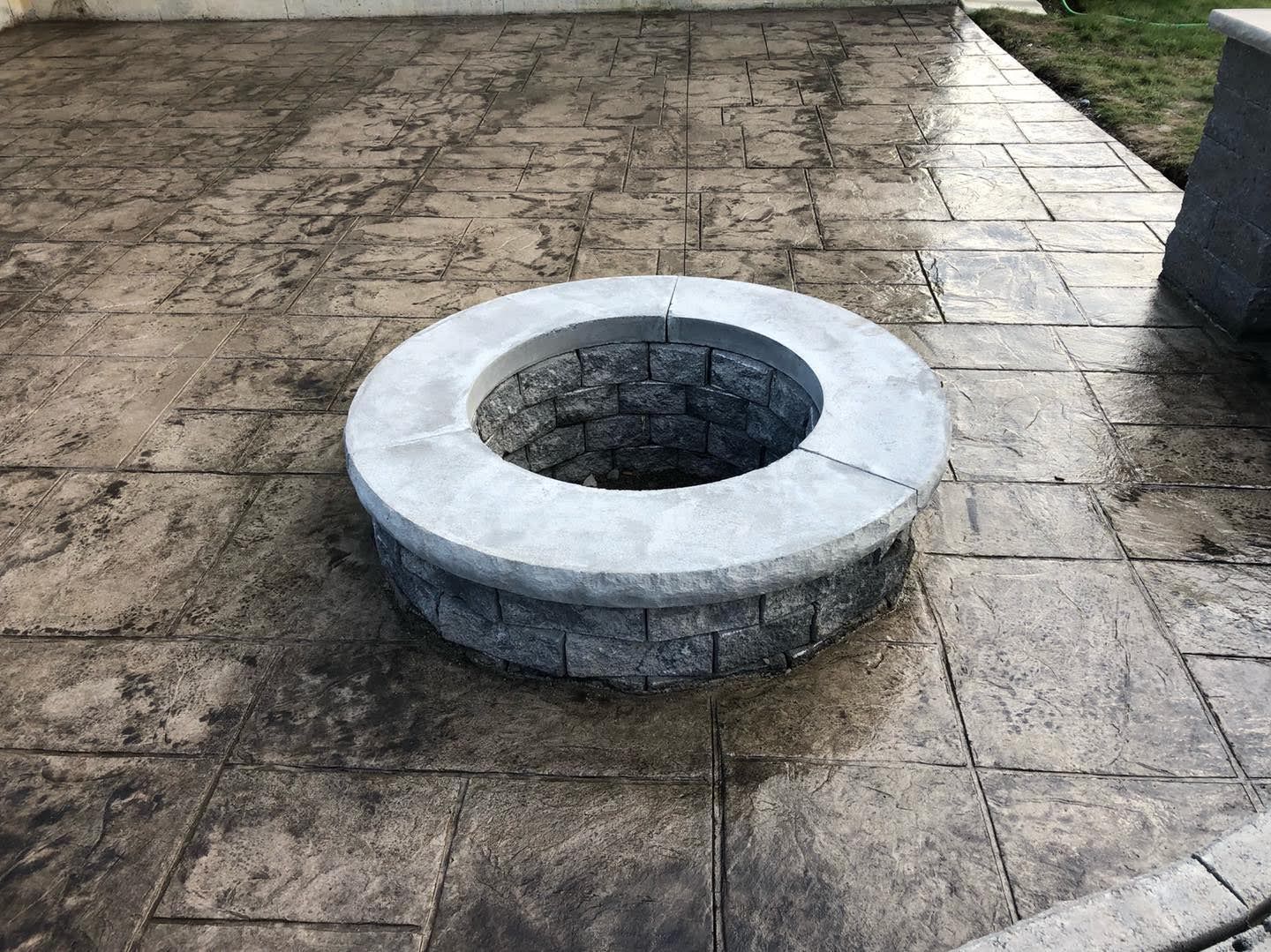 Fire pit made of stone on a stamped concrete patio.