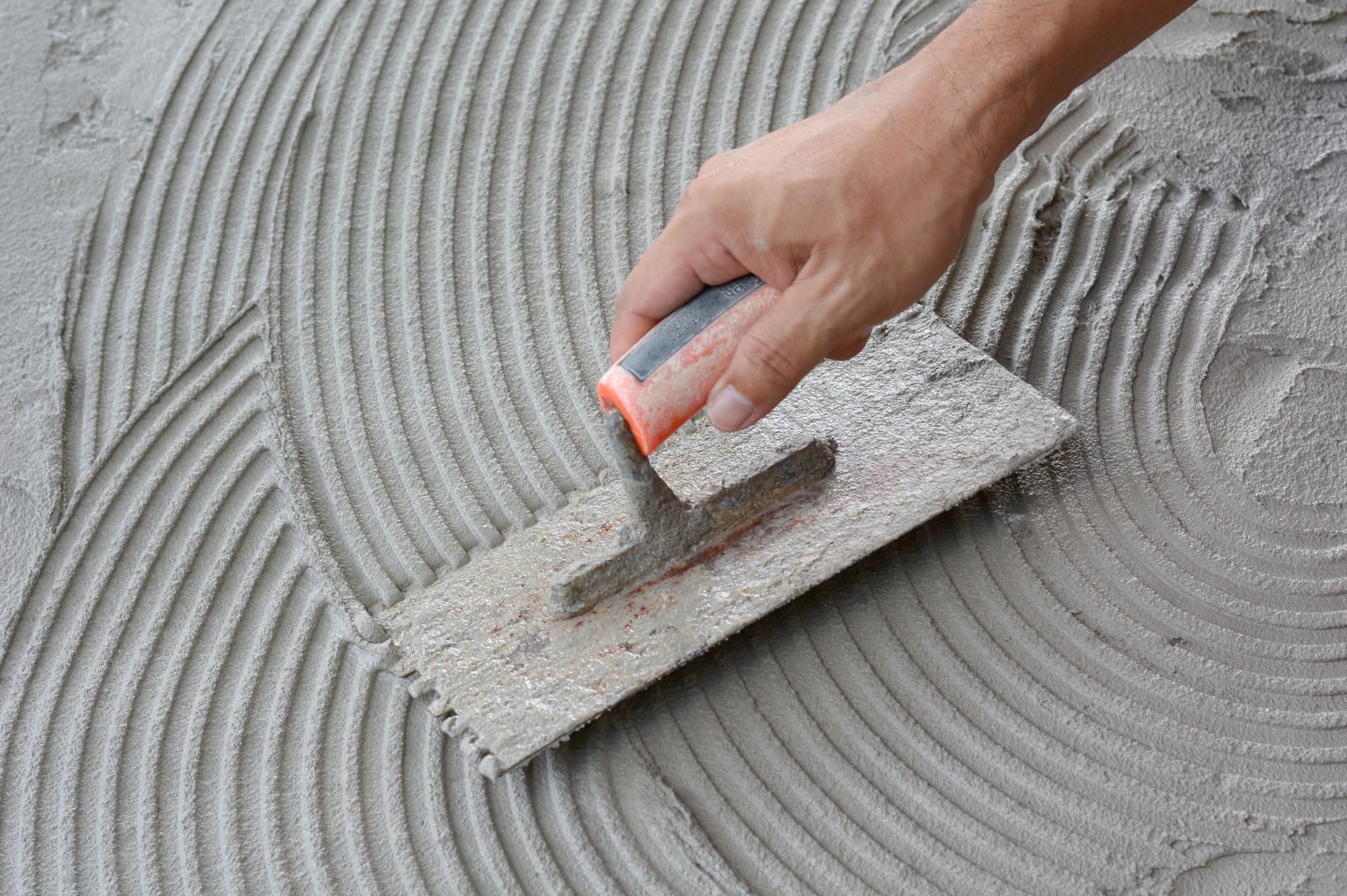 Hand smoothing the surface using a trowel on wet cement during a concrete service project.