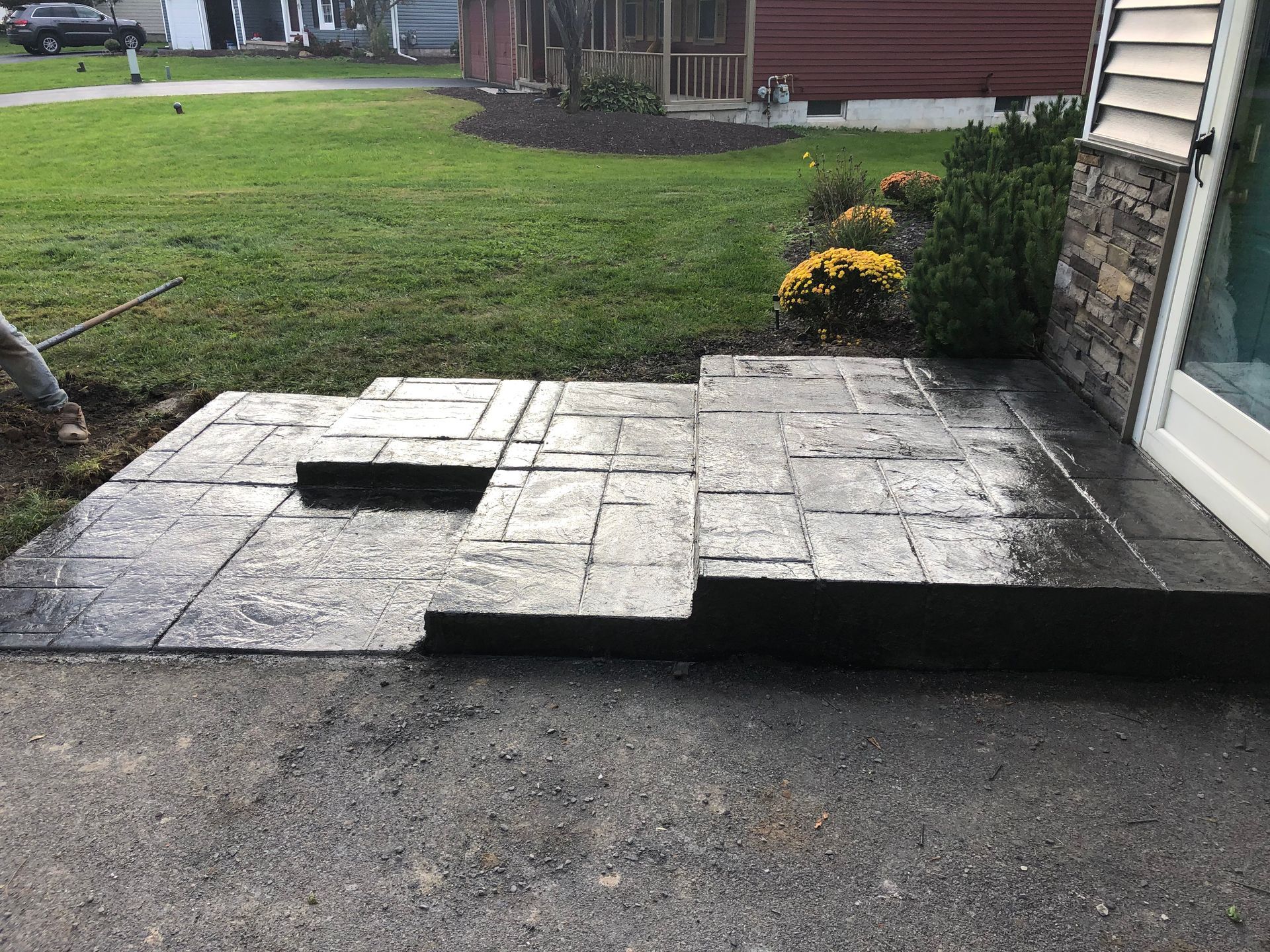 Concrete steps leading to a house entrance; part of a driveway visible; grass, flowers.