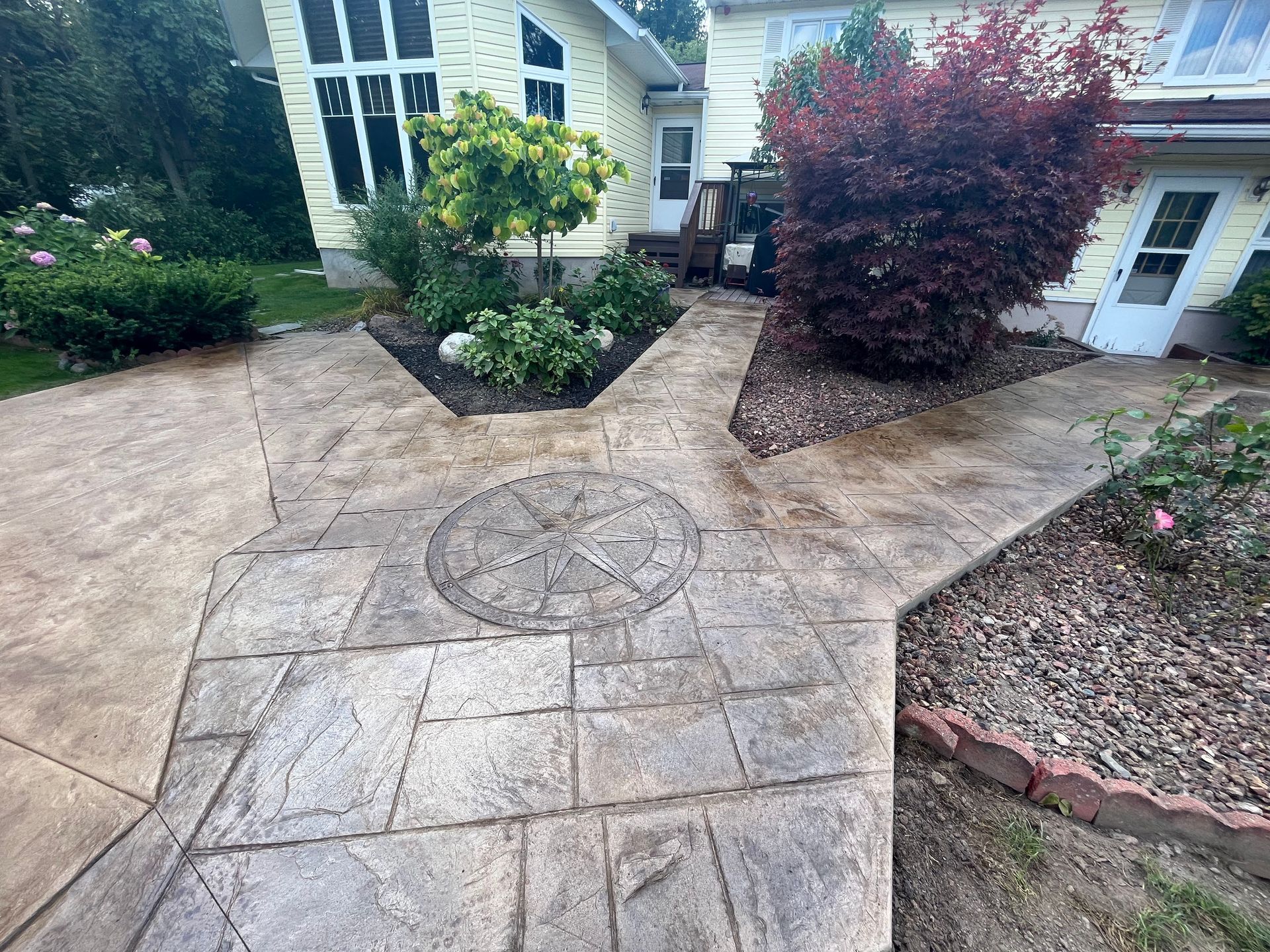 Stamped concrete patio and walkways with a flowerbed, yard, and a house.
