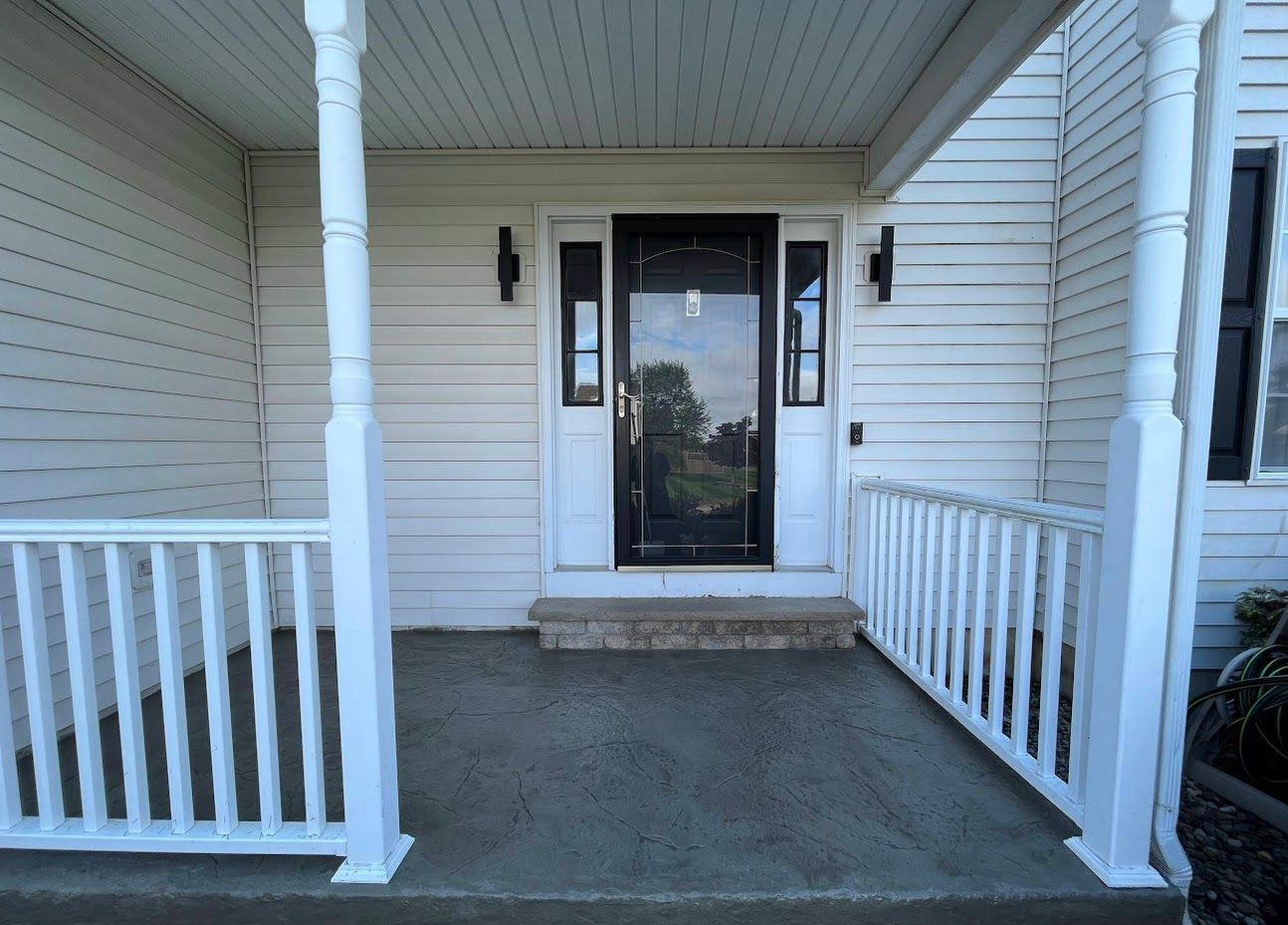 White front porch with railings and a black door with the number 3.