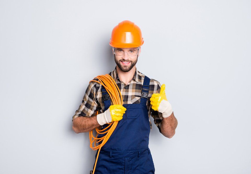 A Man Wearing a Hard Hat and Overalls is Holding a Wire and Giving a Thumbs Up — NQBC Pty Ltd in Bowen, QLD