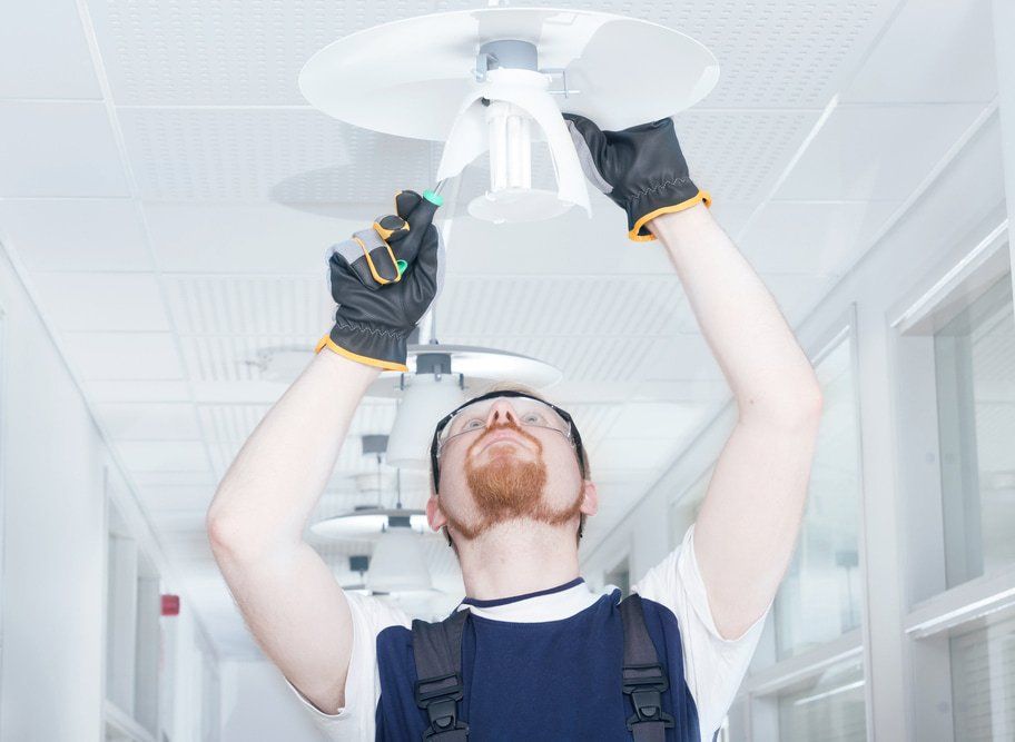 A Man is Changing a Light Bulb in a Hallway — NQBC Pty Ltd in Bowen, QLD