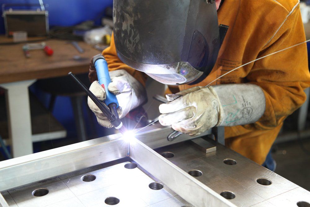 A Man is Welding a Piece of Metal in a Factory — NQBC Pty Ltd in Bowen, QLD