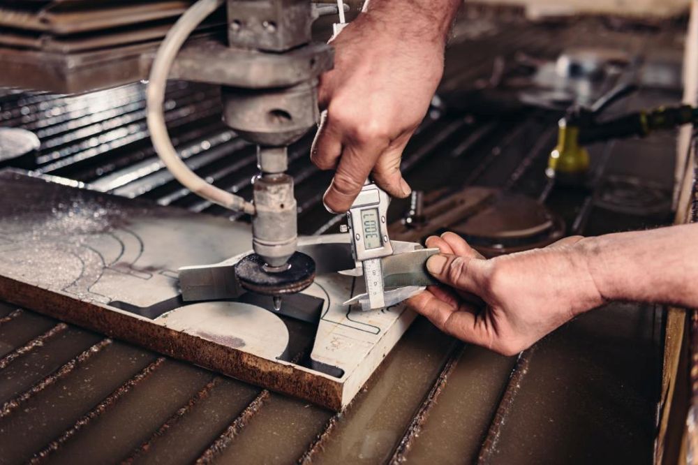 A Man is Measuring a Piece of Metal With a Caliper — NQBC Pty Ltd in Moranbah, QLD