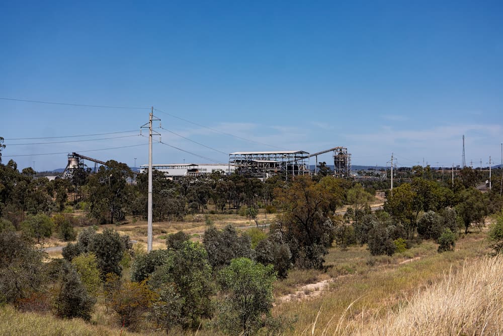 There is a Large Building in the Distance Surrounded by Trees and Power Lines — NQBC Pty Ltd in Moranbah, QLD