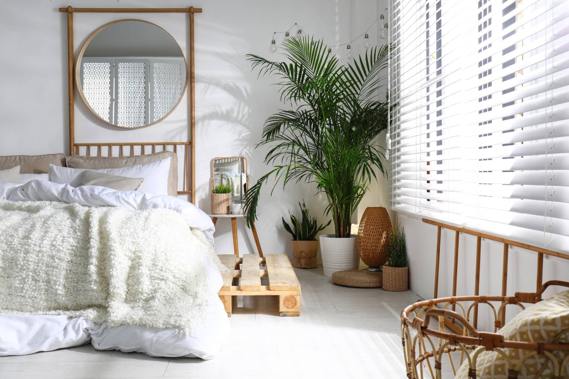 Boho chic bedroom with wooden mirror, boho accents, and white window blinds.
