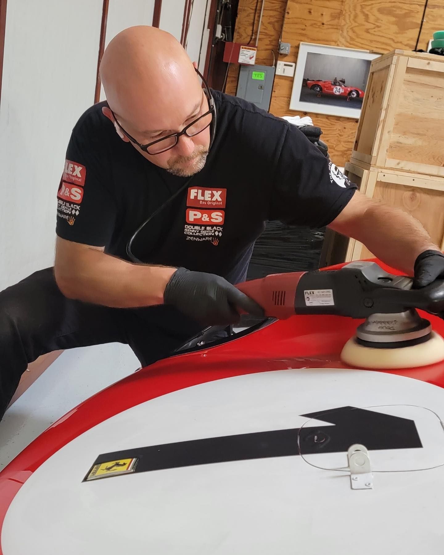 Man polishing red and white vehicle, wearing black gloves and Flex shirt.