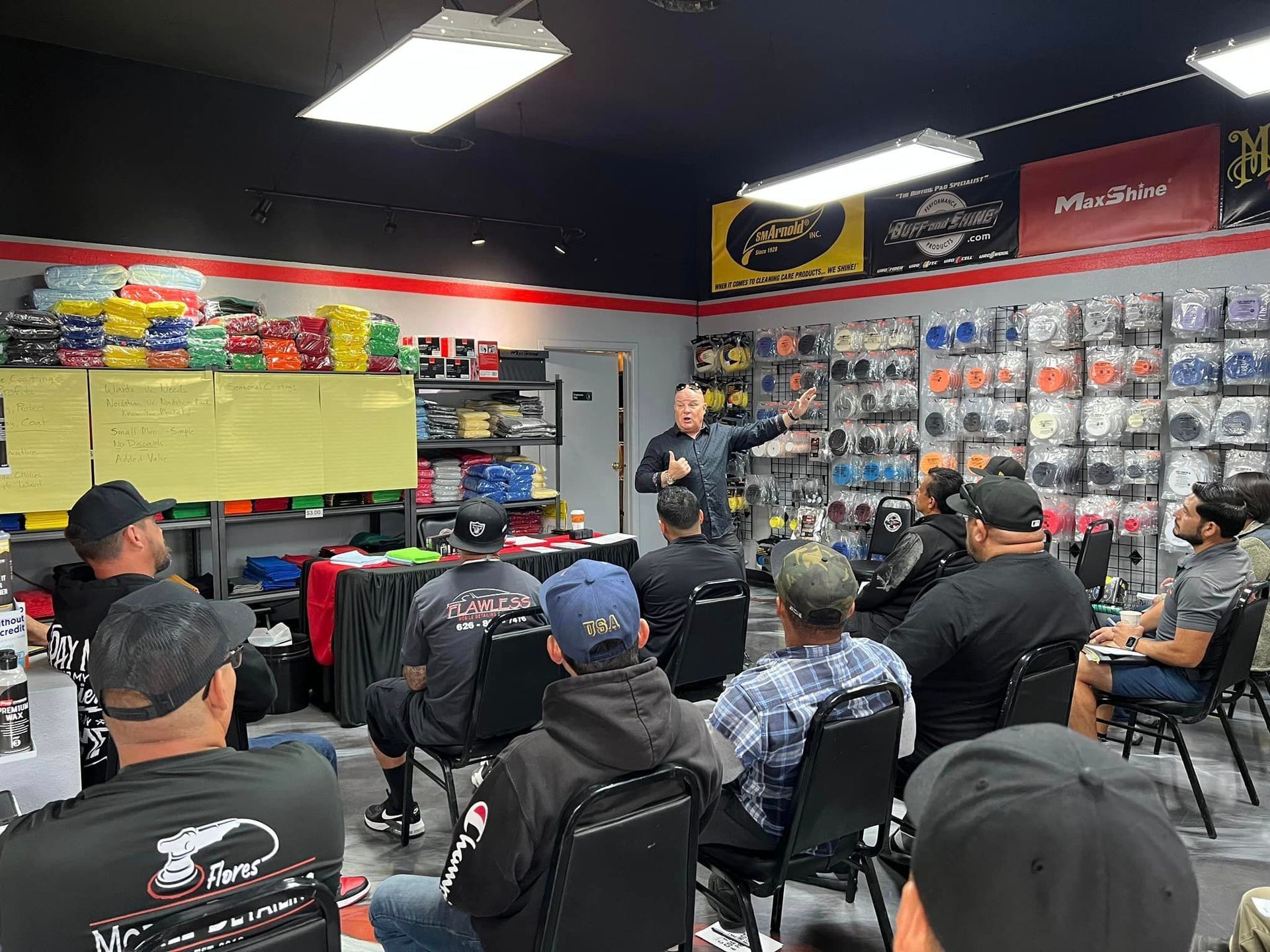 A man giving a presentation to a group in a store with car parts.