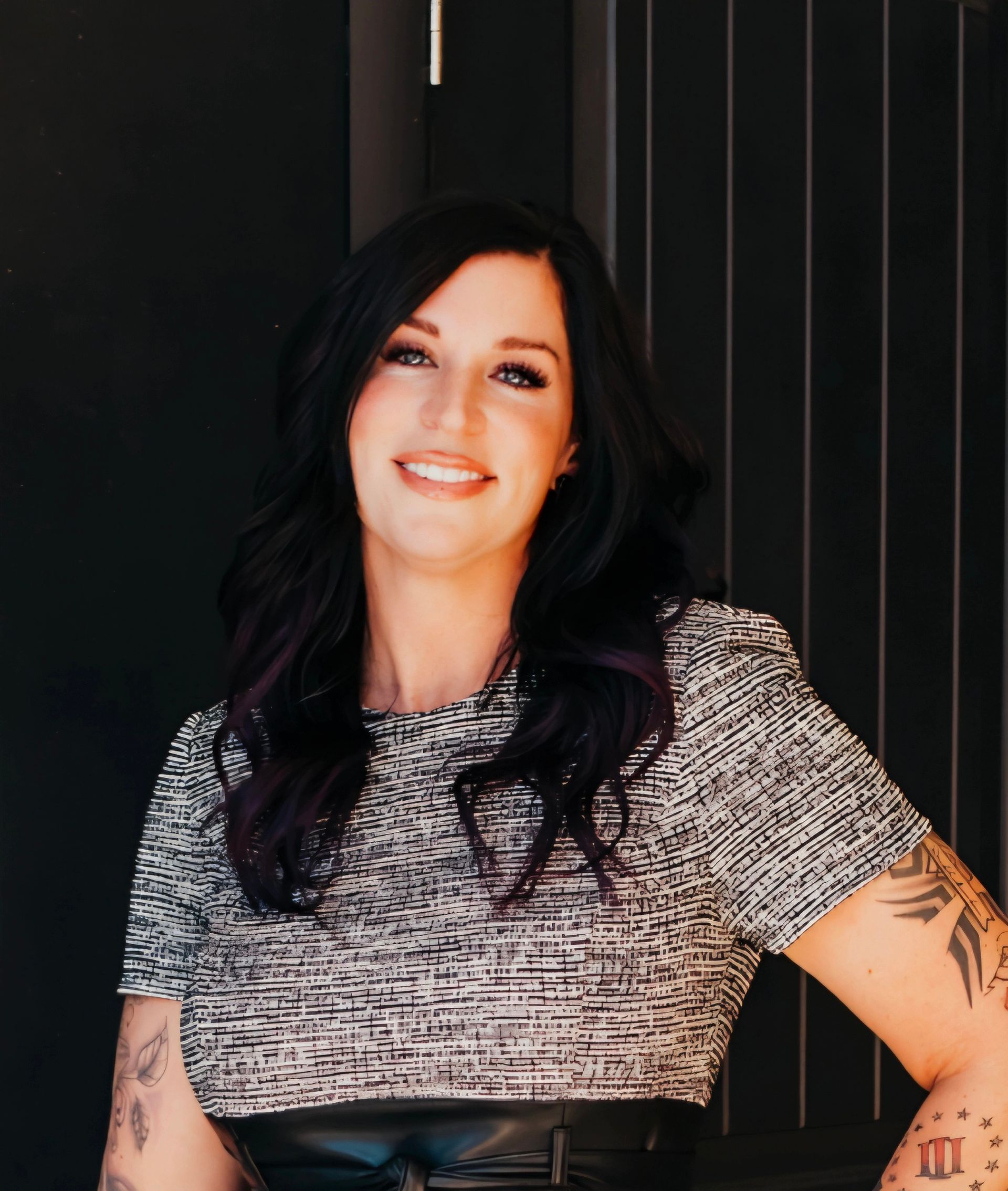 A woman with a tattoo on her arm is smiling for the camera.