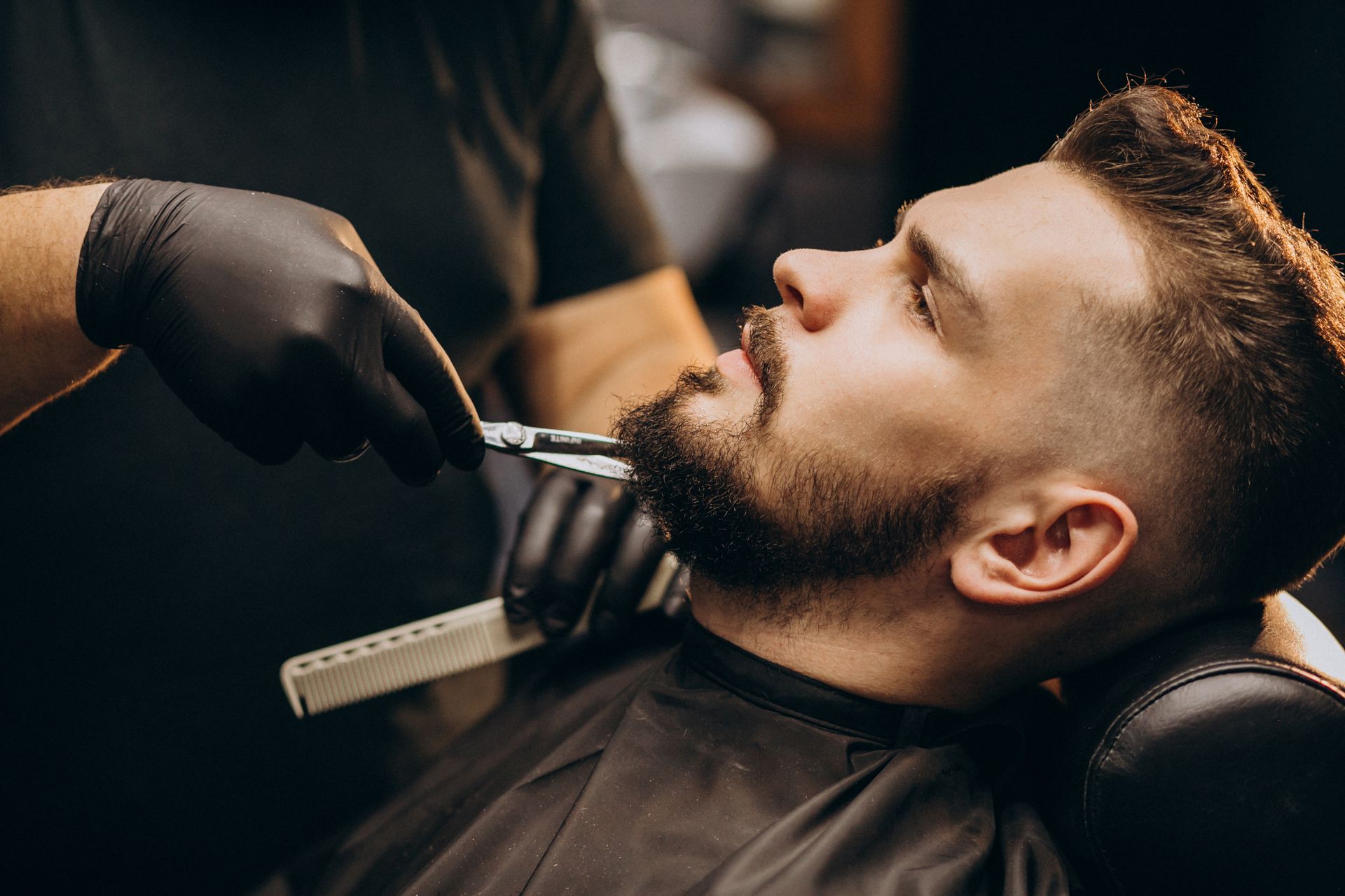 A man is getting his beard shaved by a barber in a barber shop.