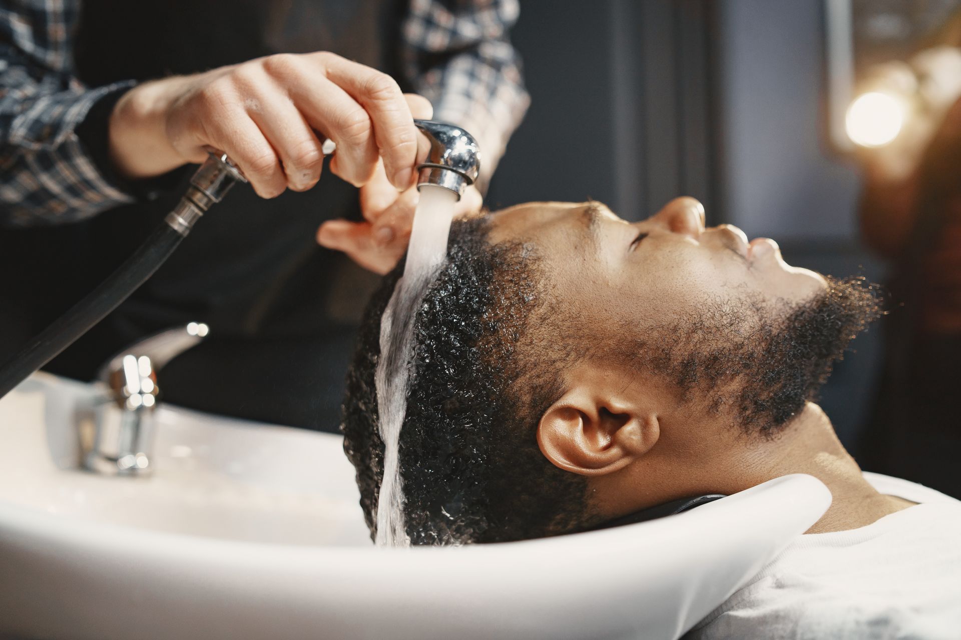 A man is getting his hair washed at a barber shop.
