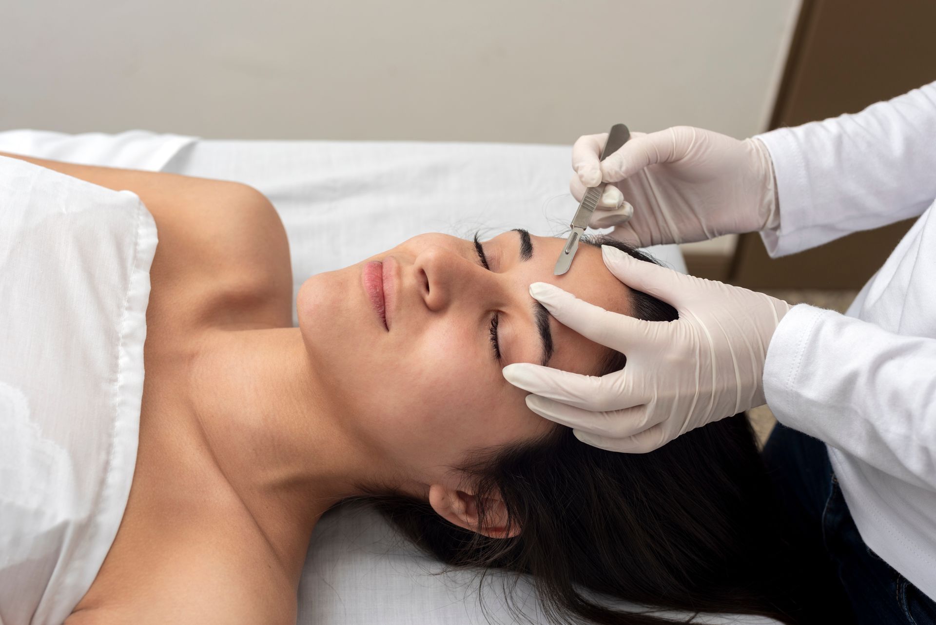 A woman is laying on a bed getting a facial treatment.