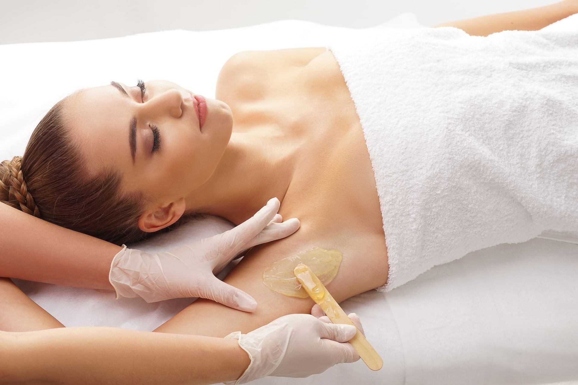 A woman is getting her armpit waxed in a beauty salon.