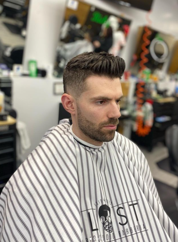 A man is getting his hair cut at a barber shop.