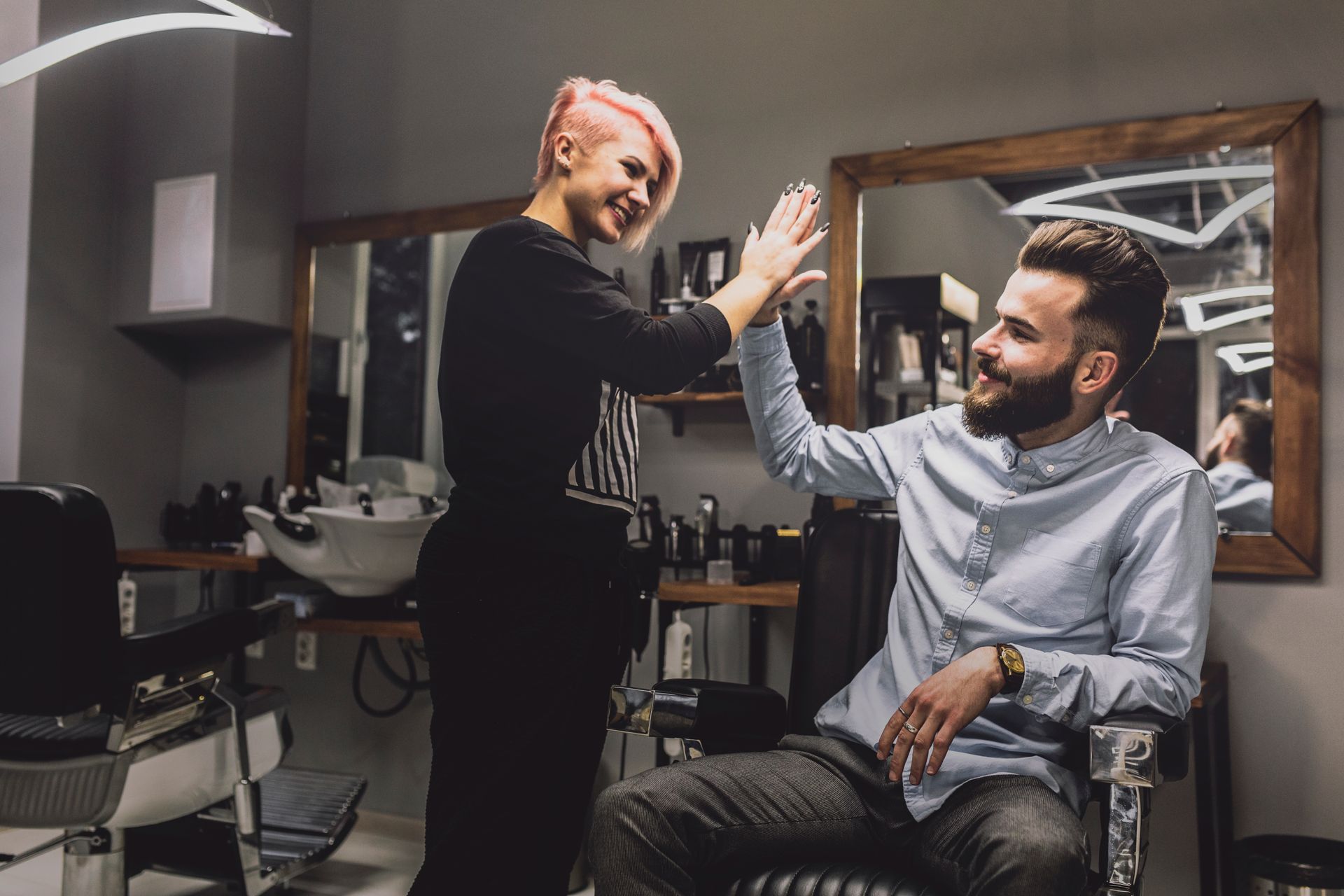 A woman is giving a man a high five in a barber shop.