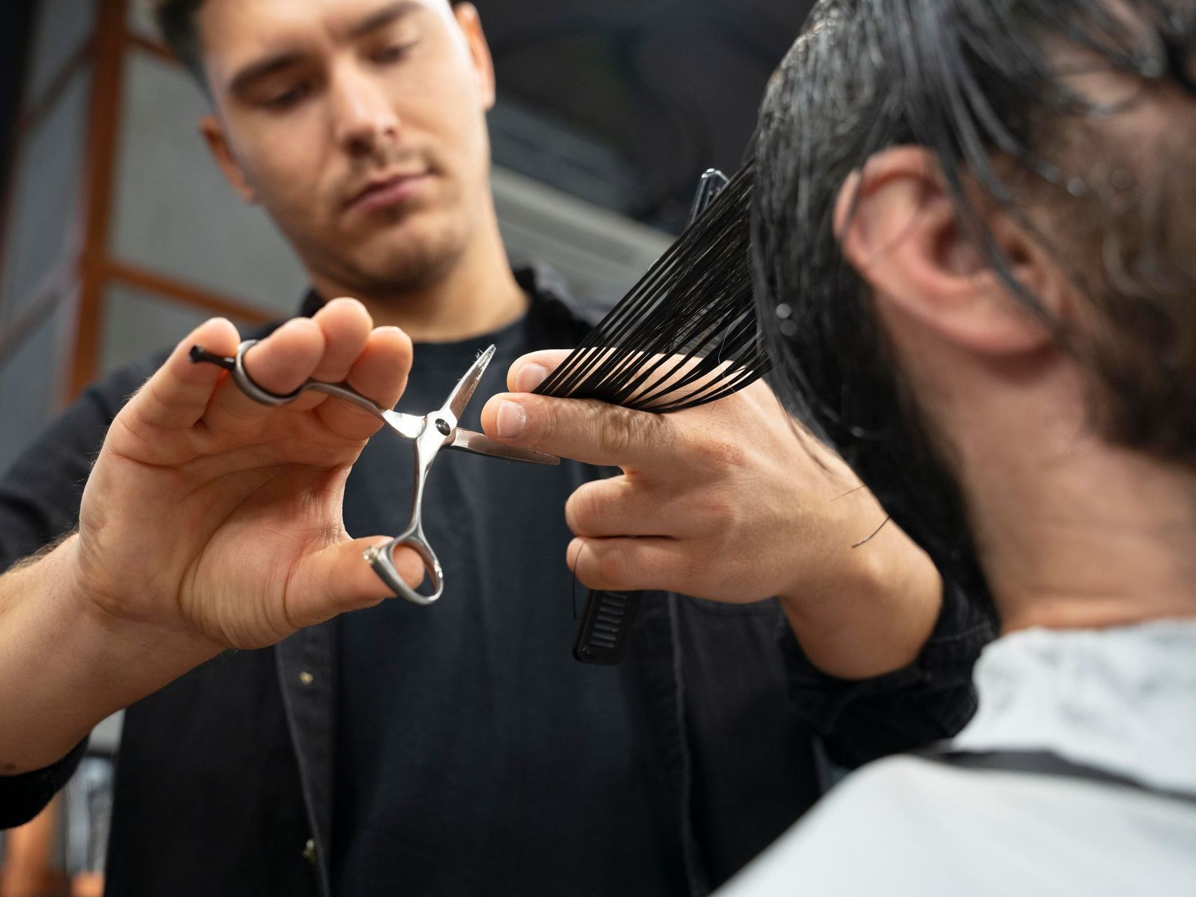 A man is getting his hair cut by a barber.