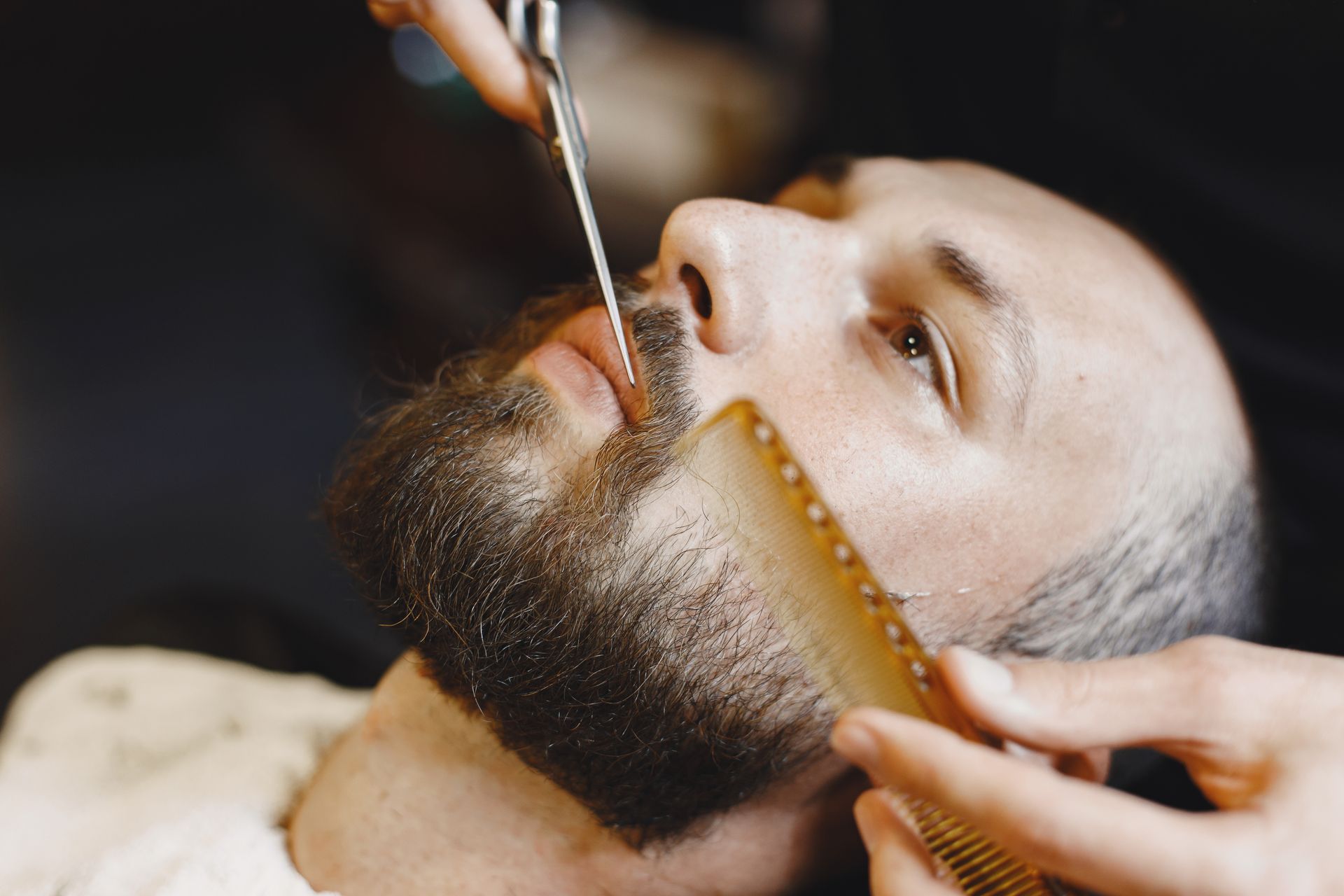 A man is getting his beard shaved by a barber.