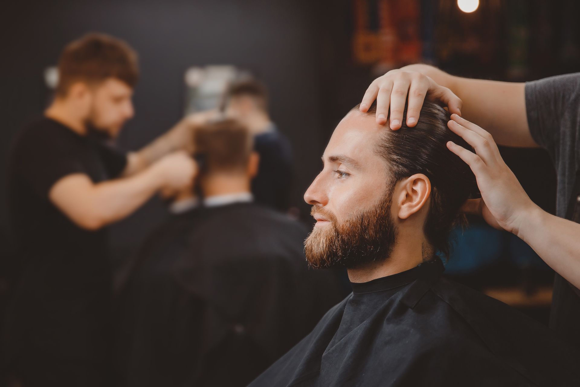 A man is getting his hair cut at a barber shop.