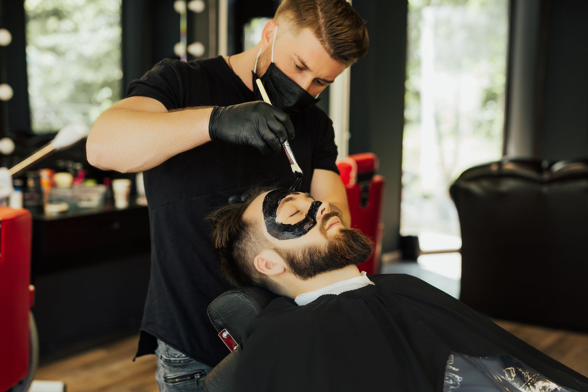 A man is getting his beard shaved by a barber in a barber shop.