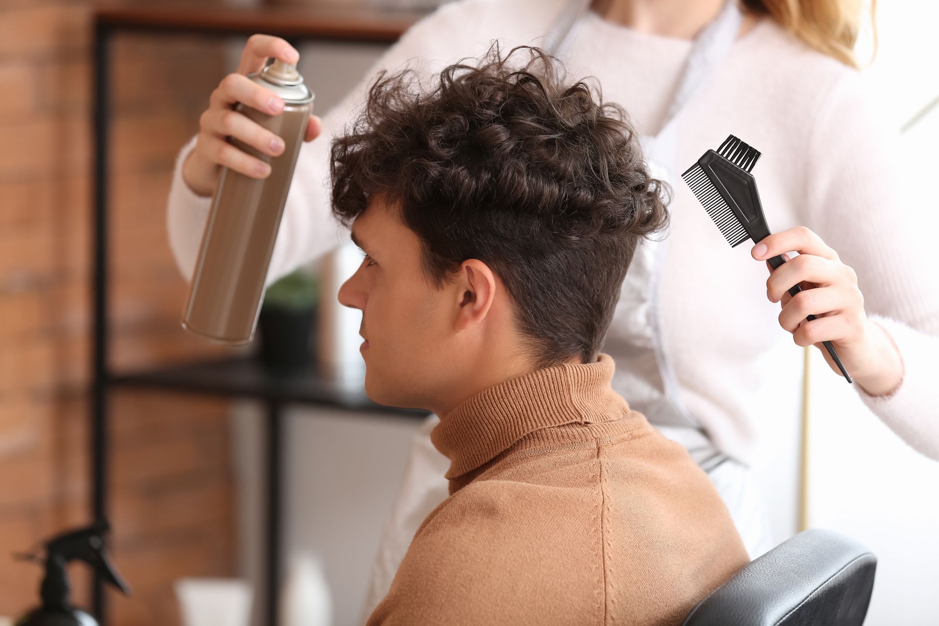 A man is getting his hair cut by a woman in a salon.