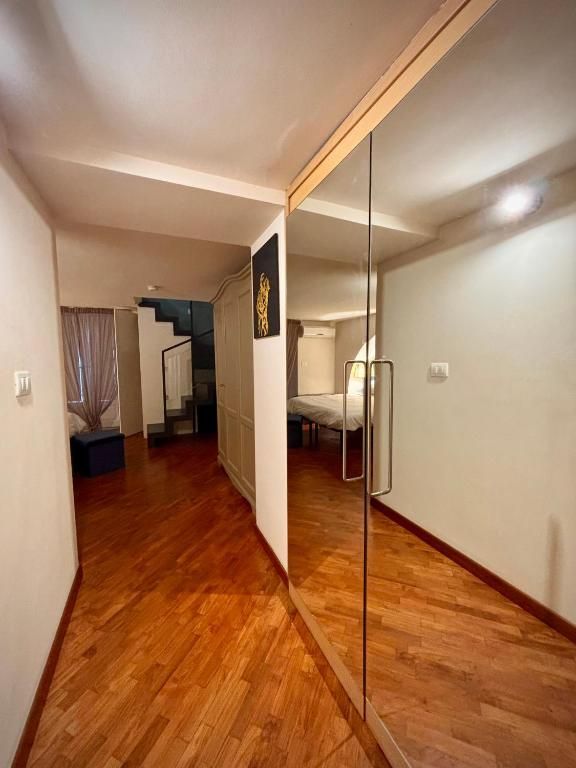 Corridoio stretto con pavimento in legno, porta dell'armadio a specchio e porta per le scale.