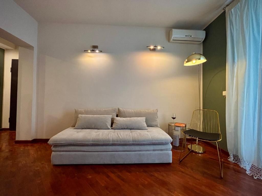 Accogliente soggiorno con letto, sedia dorata, lampada da terra e pareti bianche e verdi.