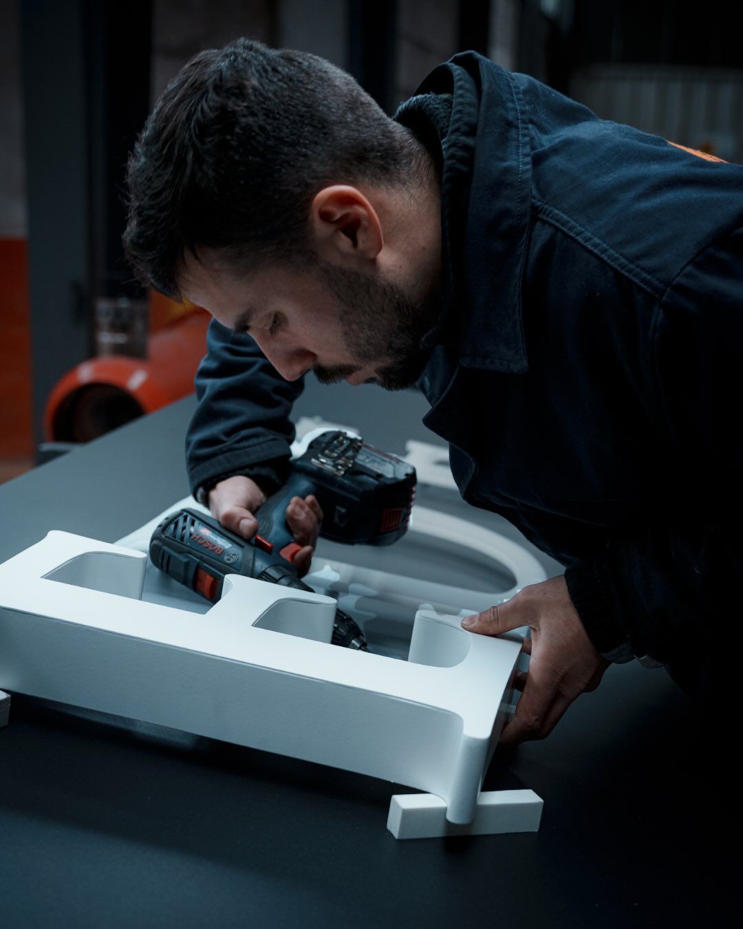 Una persona utilizza un trapano elettrico per assemblare una grande lettera 