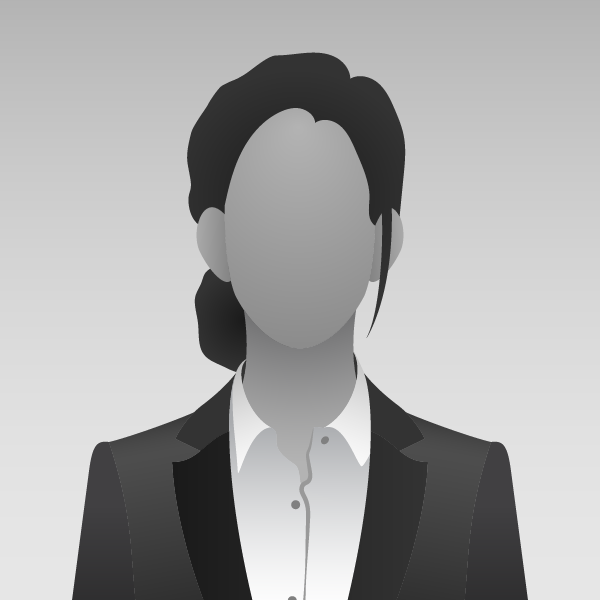 Woman in a business suit, hair tied back in a low ponytail, neutral expression.