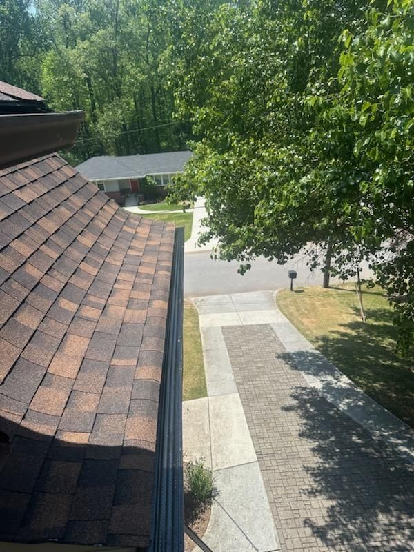 An aerial view of a roof with a gutter and trees in the background.