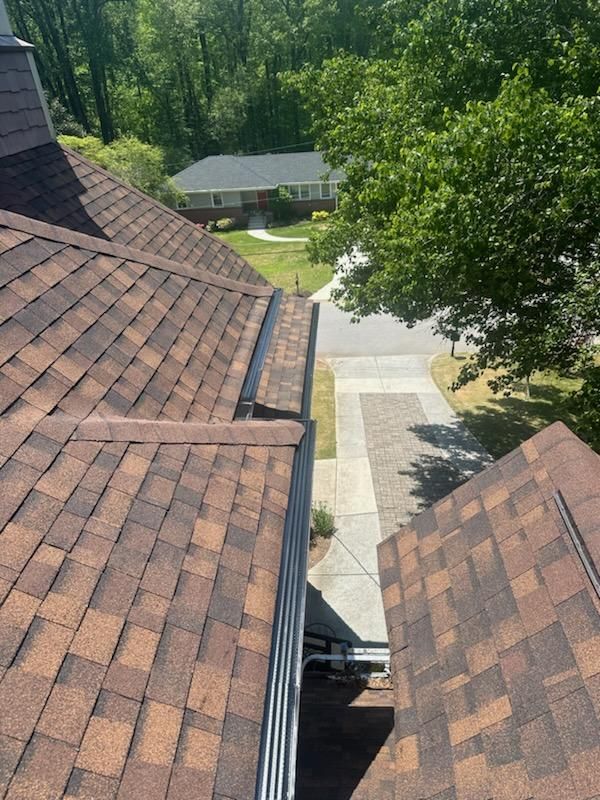 An aerial view of a roof of a house with trees in the background.