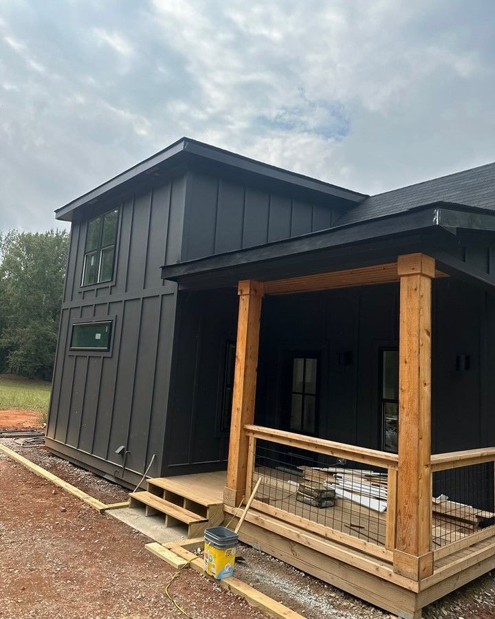 A black house with a wooden porch is being built.