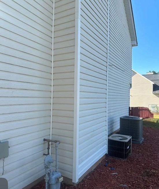 A white house with a black air conditioner on the side