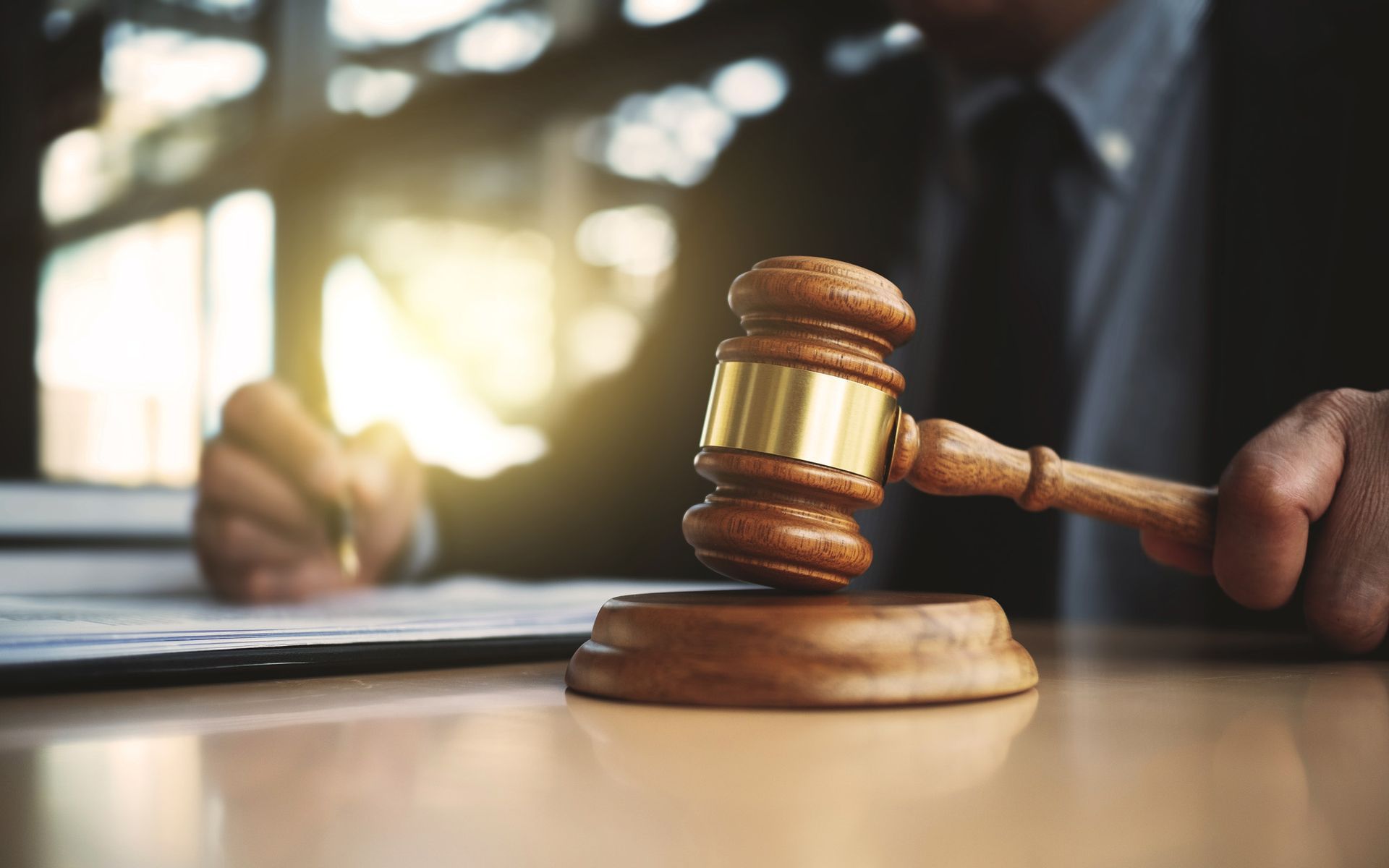 A judge is sitting at a table holding a wooden gavel.