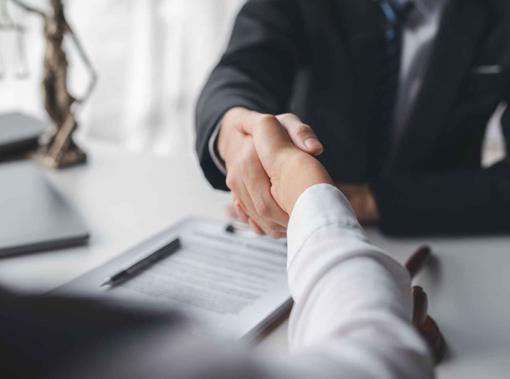 A man in a suit and tie is shaking hands with a woman in a white shirt.