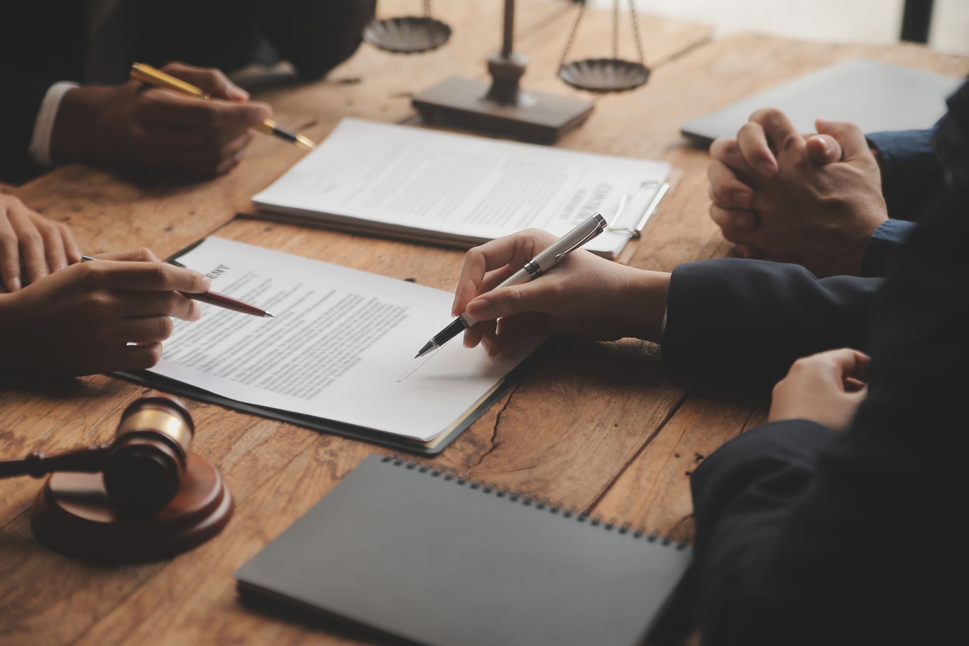 A group of people are sitting around a wooden table signing papers.
