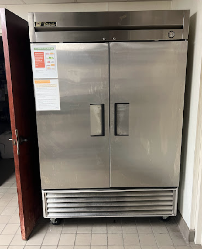 A stainless steel refrigerator is sitting next to a door