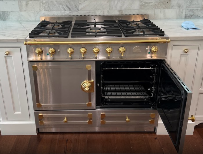 A stainless steel stove top oven with the door open