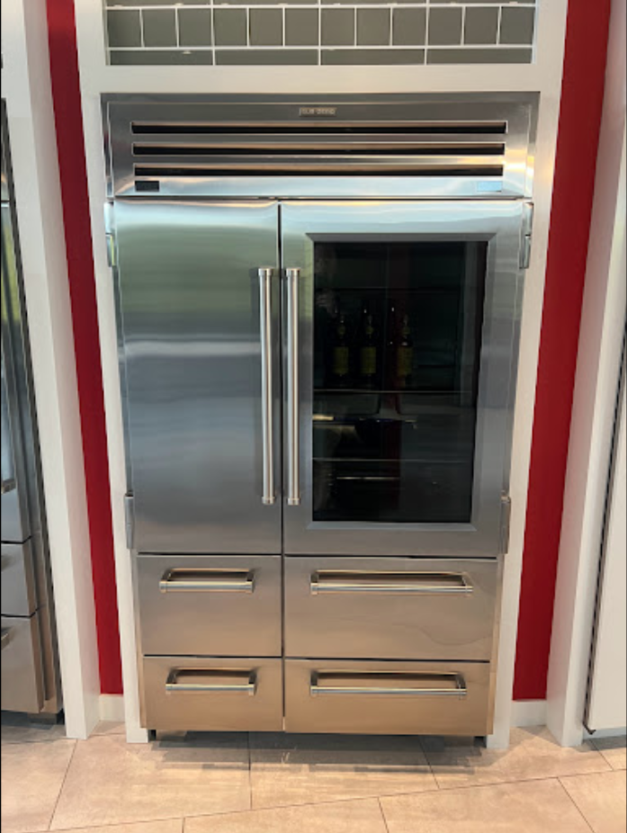 A stainless steel refrigerator with a glass door and drawers in a kitchen.