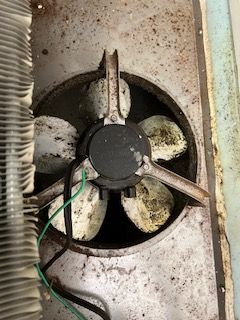 A close up of a dirty fan on a refrigerator.