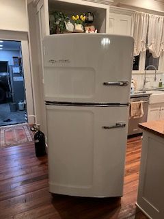A white refrigerator is being repaired in Senoia by John's Heating, Cooling, and Appliance Repair