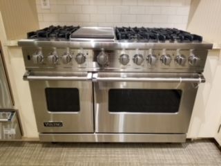 A stainless steel oven is sitting on a tiled floor in a kitchen.